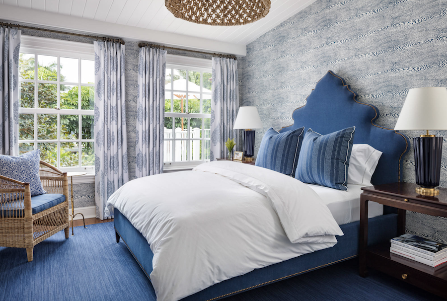 blue upholstered bed in bedroom with wallpaper