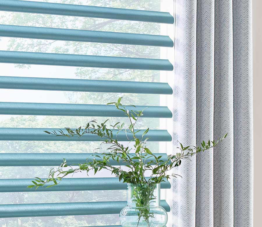 detail of blue piroutte window shades and designer drapes next to house plants