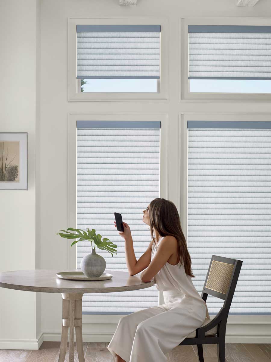 woman sitting with phone in dining room with sonnette cellular roller shades