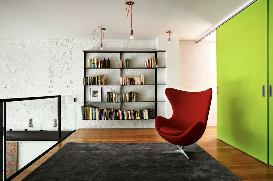 Neon green wall with a red accent chair and bookshelves