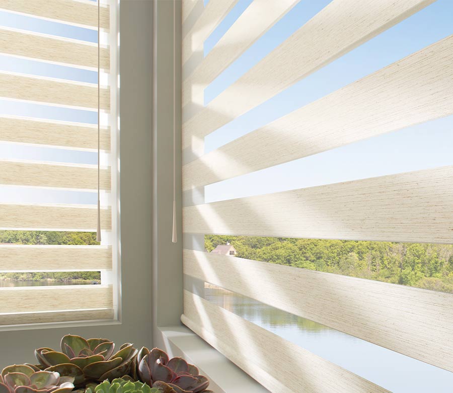 Banded shades in cream fabrics next to succulents overlooking a tranquil lake