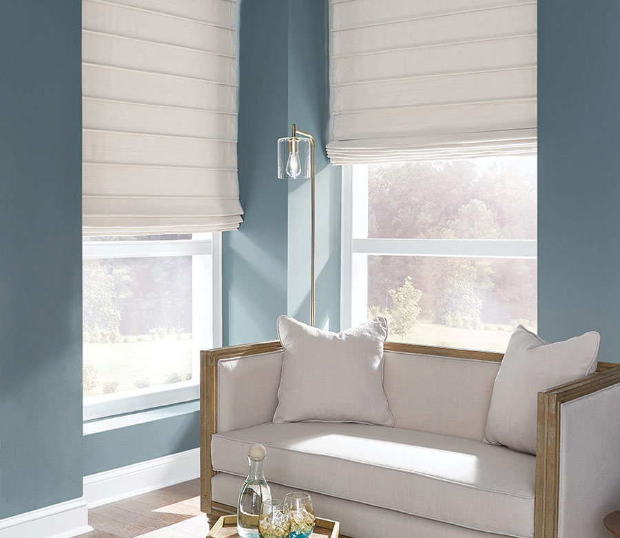 cream fabric shades in corner window blue walls and settee