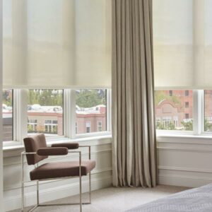 Custom drapery layered with Designer Roller Shades in a comfortable sitting area