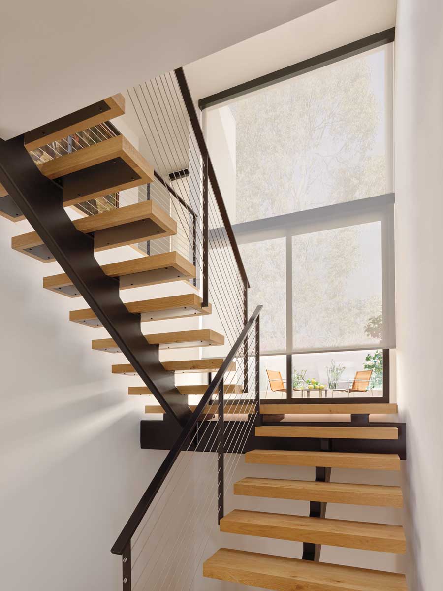 Designer Solar Shades covering windows on a landing in a modern stairwell at a home.