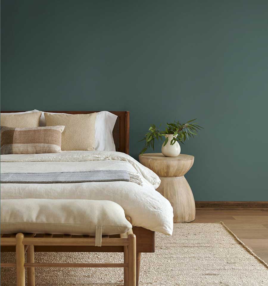 a green teal wall color that has a bed and nightstand against it