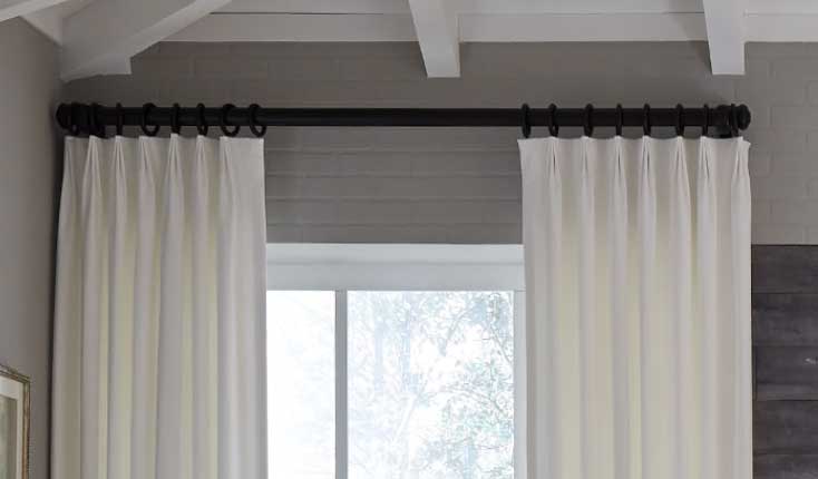 Inverted Pleat Header Style in a dark gray room with a blind cutain rod and neutral white curtains