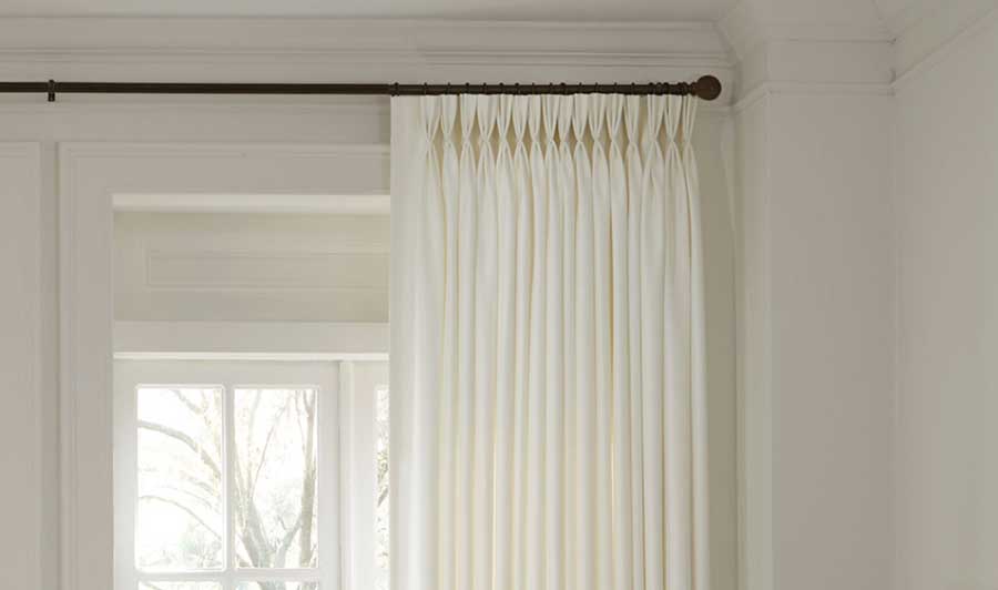 a close up of triple pleat pinch pleat drapery that is in a neutral toned room