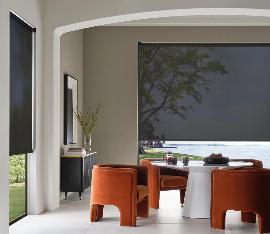 black designer screen shades in living room with orange chairs